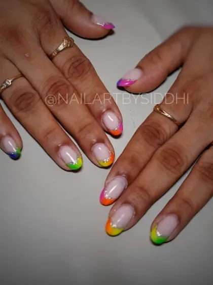 A playful rainbow French manicure, with each nail tip painted in a different bright color.