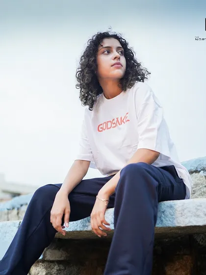 A model wearing the white Godsake graphic tee. The oversized fit provides a comfortable and stylish drape, perfect for a relaxed look.