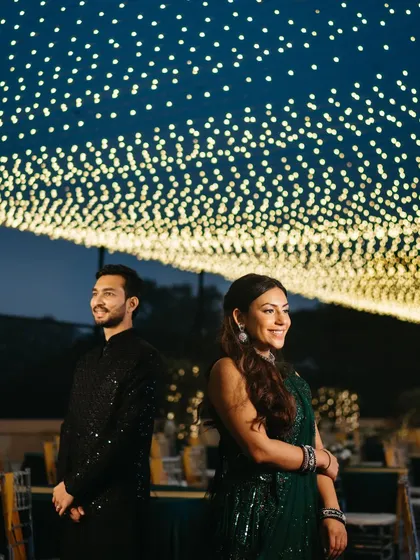 A beautiful portrait of the couple standing back-to-back under the starry canopy of lights, full of anticipation for the night ahead.