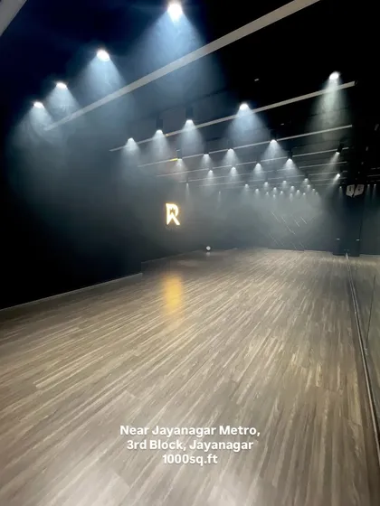 Welcome to my Jayanagar studio. This is the moody, cinematic space you've been looking for, complete with professional track lighting, a smoke machine for atmosphere, and our signature 'R' logo wall. It's a 1000 sq.ft canvas ready for your next dance video, rehearsal, or photoshoot.