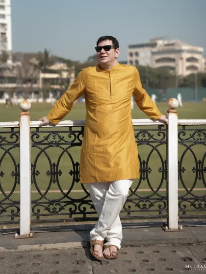 The groom, embracing the traditions of his bride's culture, stands proudly in his yellow kurta. This portrait captures a moment of calm and confidence during the vibrant Haldi festivities.
