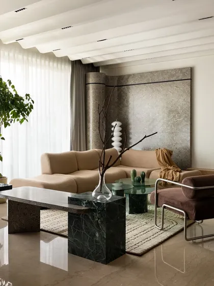 Another perspective of the living room, highlighting the custom marble bench and the way it complements the soft curves of the bouclé sofa. The space is a careful balance of hard and soft materials.