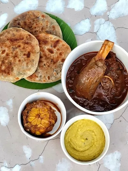 Our signature Champaran Mutton, deconstructed for delivery. You get the tender, fall-off-the-bone meat in its rich, rustic gravy, paired with flaky Sattu Parantha, roasted garlic, and a sharp mustard chutney. It’s a complete, hearty meal, packed to preserve every element.