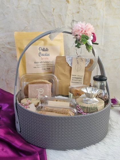 A grey woven basket filled with a variety of our snacks, including Potato Brickles and Green Chilli Oregano Roasted Cashews. A great choice for bulk corporate orders.