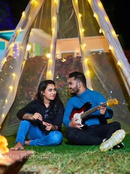 A cozy campfire scene, complete with a guitar prop and a fairy-lit teepee, creates a warm and intimate setting for a romantic night shoot.