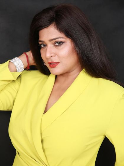 A vibrant studio headshot against a black backdrop. The bright yellow dress provides a fantastic pop of color, making the image stand out.