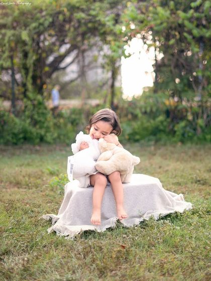 A tender moment hugging a teddy bear during her outdoor painter-themed shoot. These quiet, sweet moments are just as important as the playful ones.