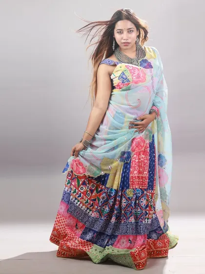 A full-length studio portrait of the Garba outfit. The clean, neutral background makes the vibrant colors of the lehenga the main focus.
