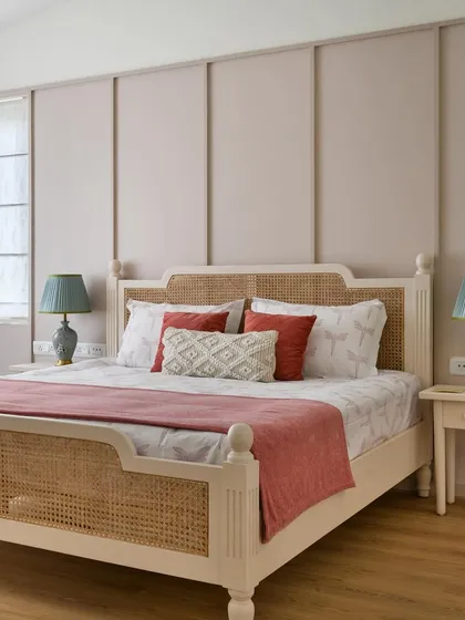 The French-inspired bedroom in 'House of Kismish' features a custom bed with cane details and a paneled wall in a delicate pastel hue.