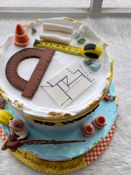 A top view of the engineer's retirement cake, showing the detailed, handcrafted tools of the trade like a protractor and measuring tape.