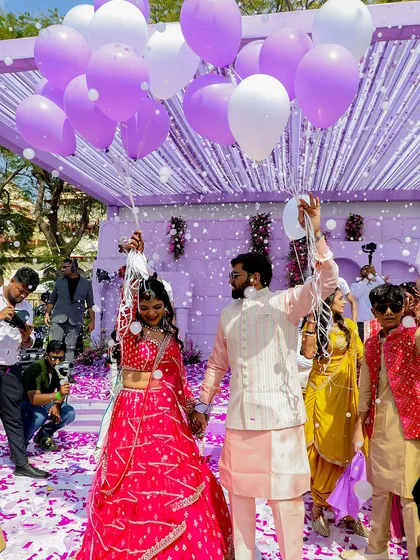 The couple makes a grand entrance at their Haldi, holding balloons as confetti rains down. I love creating picture-perfect moments that are full of life and color.