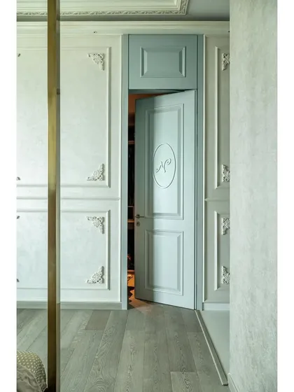 A view of the master bedroom passage, showcasing the custom-paneled doors with carved 'R' and 'N' initials, leading to the separate walk-in closets.