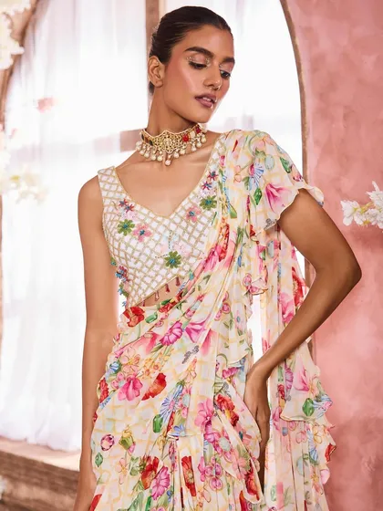 A model in a beautiful floral print ruffled saree. The makeup is soft and romantic, with a peachy-pink lip color that picks up the tones in the floral pattern.