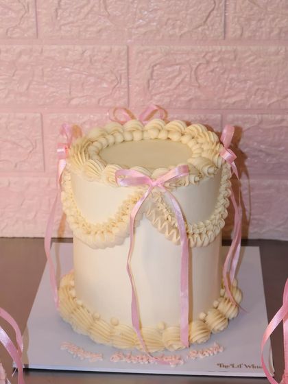 Pretty in pink bows and vintage swirls. This all-white cake with delicate pink ribbons gives us major princess vibes and is perfect for a dreamy celebration.