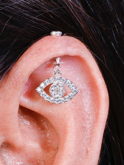 A close-up of a sparkling evil eye hanging, perfect for a helix or flat piercing.