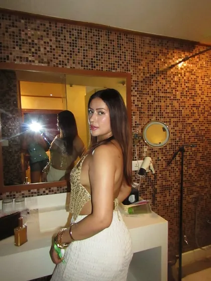 A golden hour selfie in a gold sequined halter top and white textured pants.