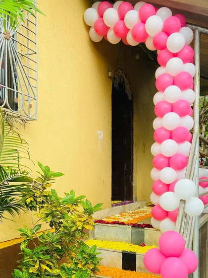 A simple pink and white balloon arch at the entrance of a home, decorated for a baby's welcome.