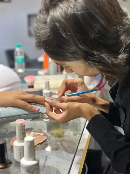 Here is one of my talented nail artists, completely focused on her craft. She is carefully applying a design with a fine brush, showing the precision that goes into every manicure.