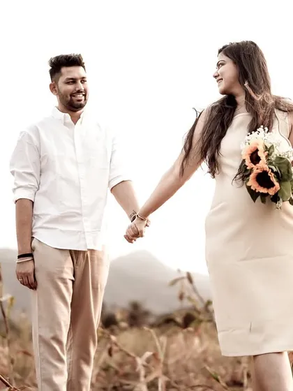 The couple walks hand-in-hand through a field bathed in the warm glow of the setting sun. This image feels like a scene from a romantic movie.