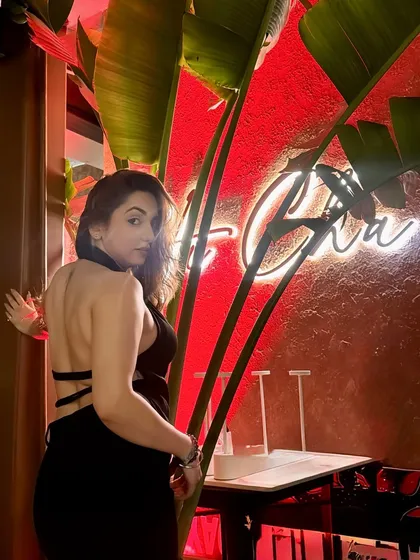 A backless OOTN shot against a neon sign at Hacha Gurgaon, blending fashion with the restaurant's cool vibe.