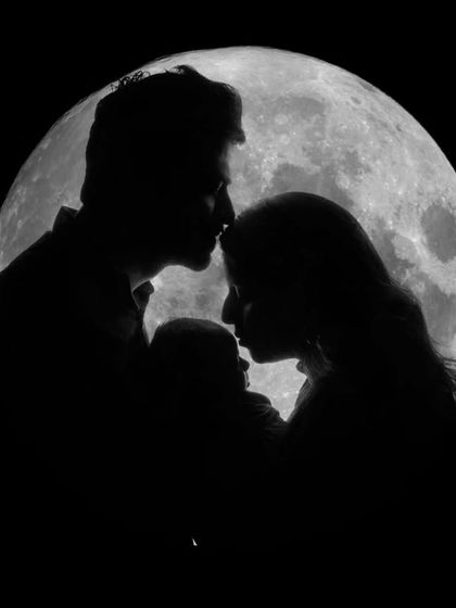 The complete family moon silhouette. Parents sharing a tender moment over their newborn, creating a perfect circle of love.