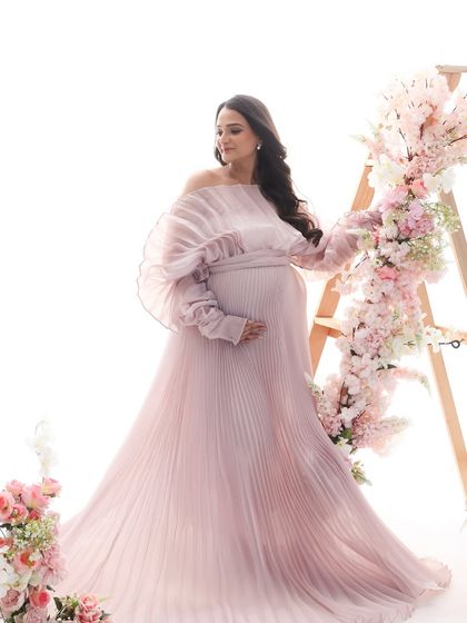 A dreamy and romantic portrait. The soft pastel pink gown and the floral ladder create a whimsical, fairytale-like setting for this beautiful mom-to-be.
