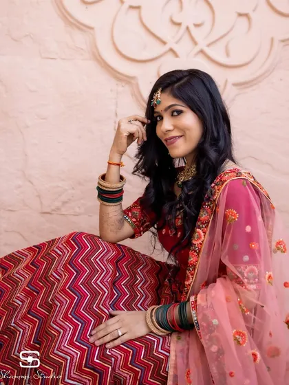 A full shot of the bride-to-be in her beautiful red and pink lehenga, perfect for an engagement or pre-wedding event.