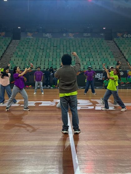 A shot from the final rehearsals on the main court at Tyagaraj Stadium. I'm guiding my dancers through the blocking and spacing to ensure the performance looks perfect from every angle in the massive venue.