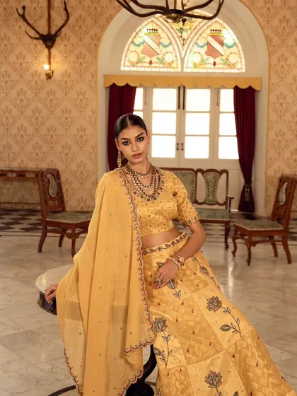 This shot captures a moment of poised elegance. The composition balances the model in her yellow lehenga with the grand archway behind her, creating a sense of depth and luxury for this ethnic wear campaign.