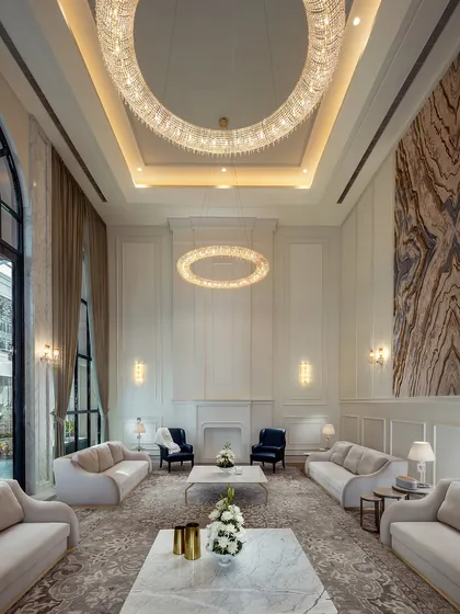 This living room in The Grand Alabaster is a study in neoclassical symmetry and scale. The double-height ceiling, circular crystal chandeliers, and classically panelled walls create a space that is both majestic and inviting. It is a retreat designed for quiet luxury and sophisticated comfort.