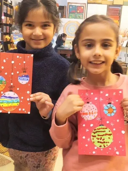 The smiles say it all. These two girls are delighted with the colorful Christmas bauble cards they designed and decorated during our festive workshop.