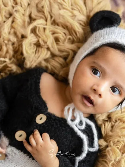 A close-up on our little panda's face, capturing his bright, curious eyes and the details of his knitted outfit.
