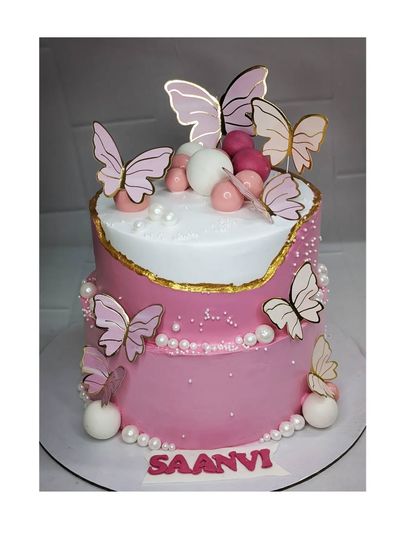 A two-tier butterfly fault line cake with two flavors: strawberry and chocolate. The design is modern and elegant, with beautiful pink butterflies and edible pearls.
