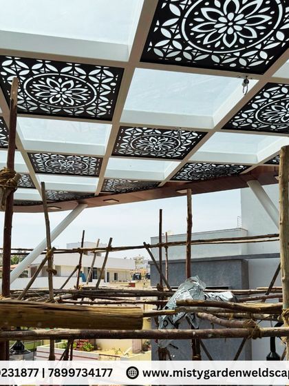 A view from below the architectural glass pergola, highlighting the intricate CNC panels. This shot shows the beautiful patterns and the quality of the fabrication work during the construction phase.