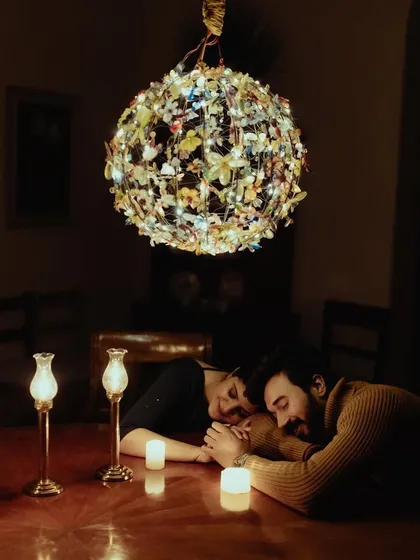 A deeply romantic and moody pre-wedding portrait, with the couple sharing a quiet moment at a candlelit table.