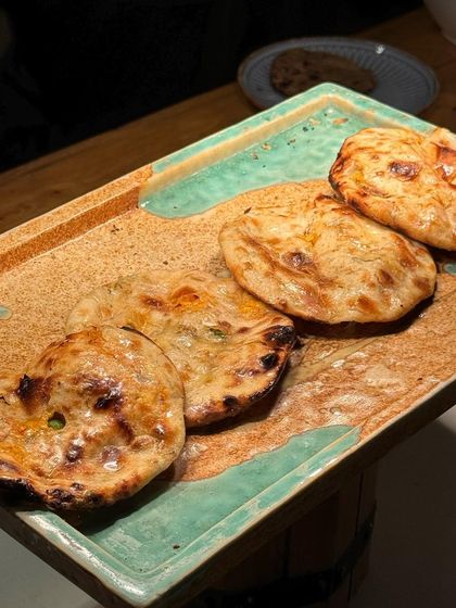 A platter of fresh, hot naans straight from the tandoor. There's nothing better than tearing into a soft, fluffy naan to scoop up a delicious curry.