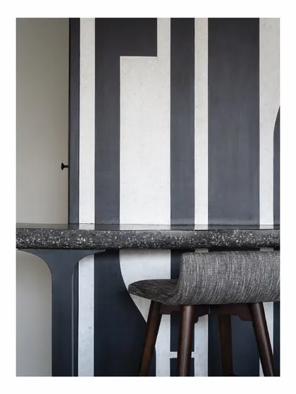 Art is integrated into every corner. This bar table in our Powai House project is set against a bold, graphic black and white panel. The abstract design acts as a powerful backdrop, transforming a functional corner into an artistic statement.