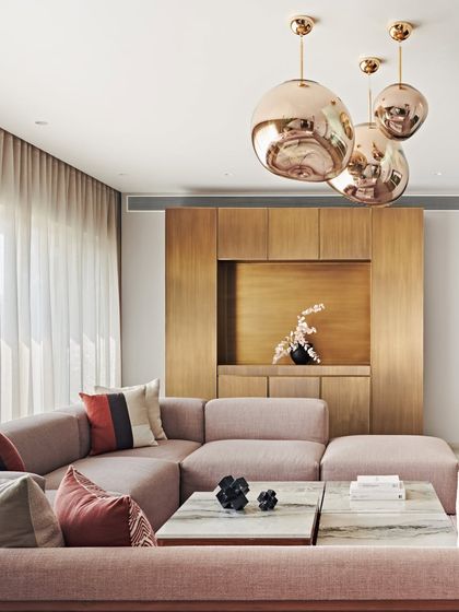 Rose-gold pendant lights add a touch of modern glamour to this living space in the Maximum City Duplex. The metallic finish contrasts beautifully with the warm wood of the custom media unit.