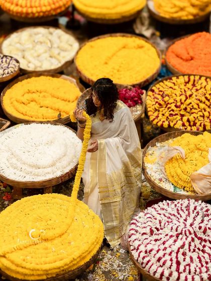 An artistic shot from above, as she interacts with a long garland of yellow flowers. The composition is a beautiful tapestry of color and texture.