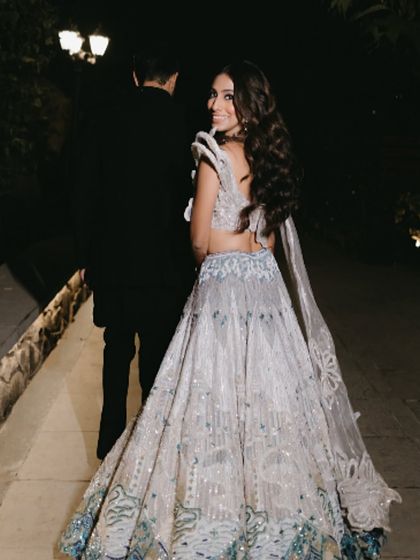 A beautiful shot of the bride from the back, showing the flow of her lehenga and her soft, wavy hair.