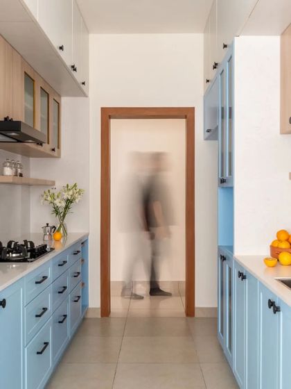 The galley kitchen is designed with powder blue lower cabinets and birch plywood upper cabinets. This use of color adds a fresh and cheerful feel to the functional space.