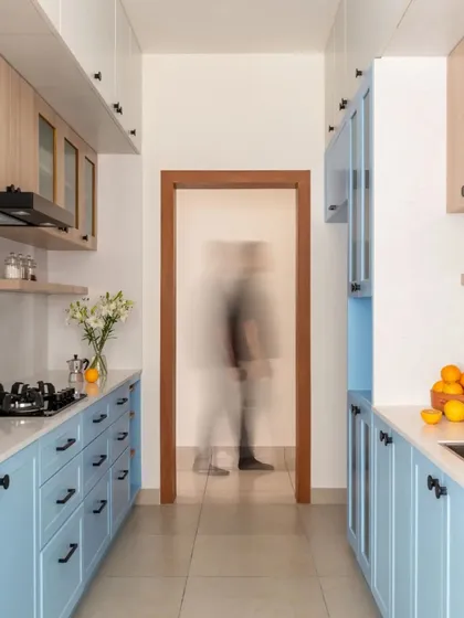 The galley kitchen is designed with powder blue lower cabinets and birch plywood upper cabinets. This use of color adds a fresh and cheerful feel to the functional space.