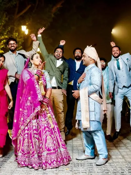 A high-energy "baraat" style photo with the couple and their friends jumping for joy.