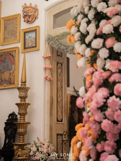 A glimpse of the decor inside the home, where a large floral installation of pink and orange carnations stands beside traditional art and a gilded decorative piece.