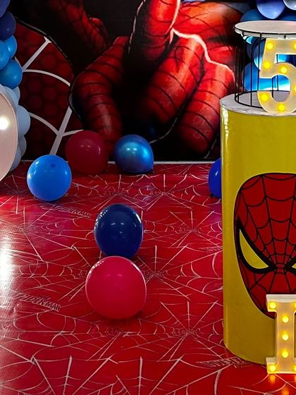 A Spiderman-themed pedestal and a light-up number '5' cage. The floor mat with a spiderweb design completes the look for this superhero celebration.