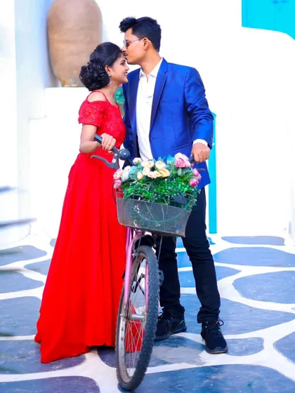 A cute and romantic pre-wedding photo with a bicycle prop. The groom kisses the bride's forehead, creating a sweet, memorable moment.