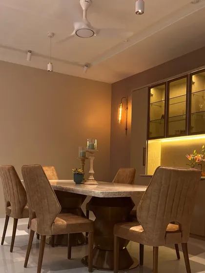 A wider view of the dining area, showing the track lighting and warm wall sconce that create a layered and ambient lighting scheme.