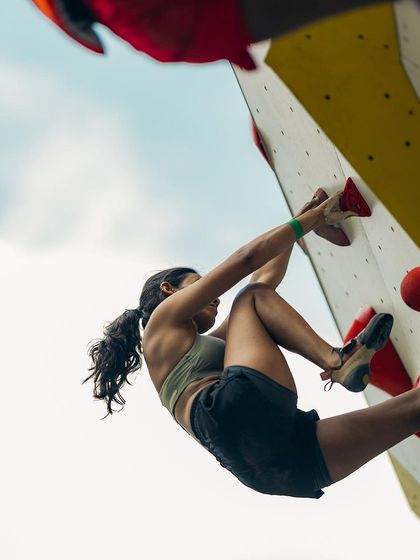 This close up shows the strength and flexibility of a climber navigating an overhang. Every muscle is engaged as she plans her next move on the bouldering route.