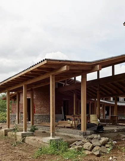 The farmhouse in Kamshet is defined by its long, covered verandas supported by a timber frame structure. These spaces provide shelter from the sun and rain while maintaining a constant connection to the surrounding landscape.