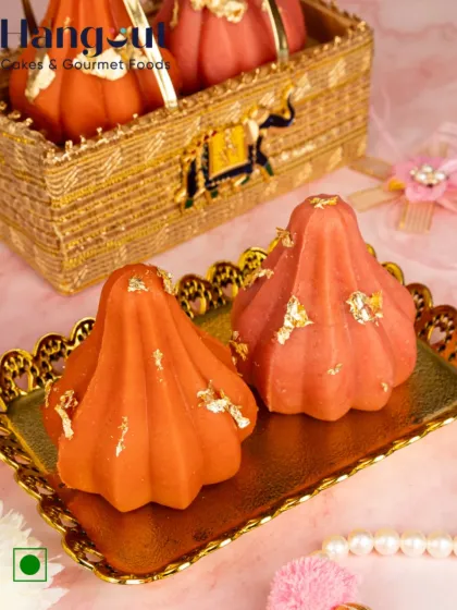This premium hamper bag is perfect for gifting. It contains two large, flavorful modaks, each bursting with festive flavor and decorated with gold foil, presented in a beautiful elephant-themed basket.
